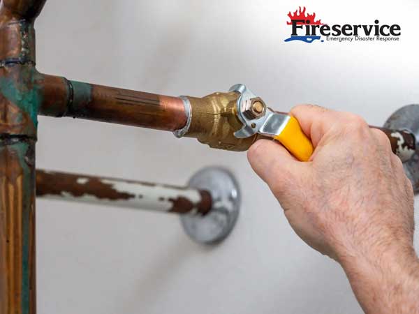 Plumber turning water shut off valve. Copper plumbing pipe with