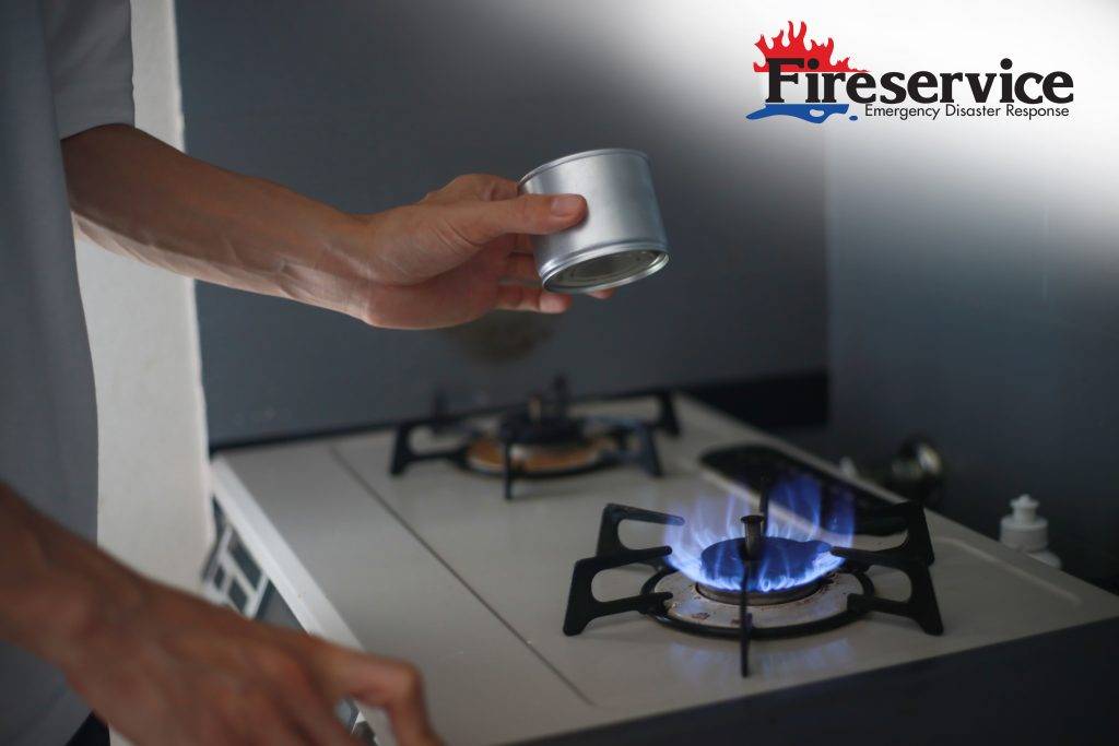 A man about to heat food on a gas stove with an exposed flame. 