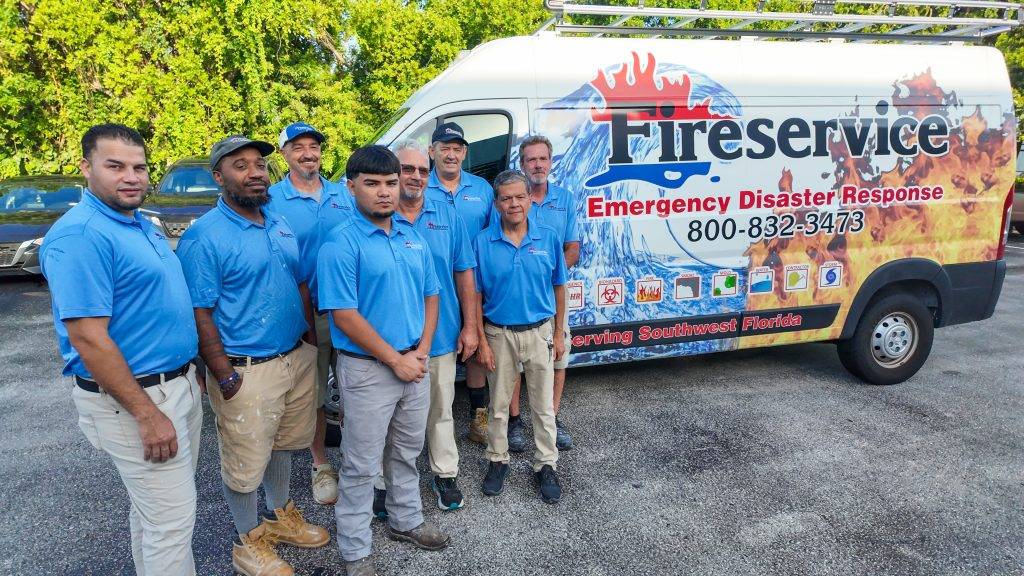 A group of men in blue shirts stand in front of a van labeled "Fireservice Emergency Disaster Response," ready for storm clean-up.