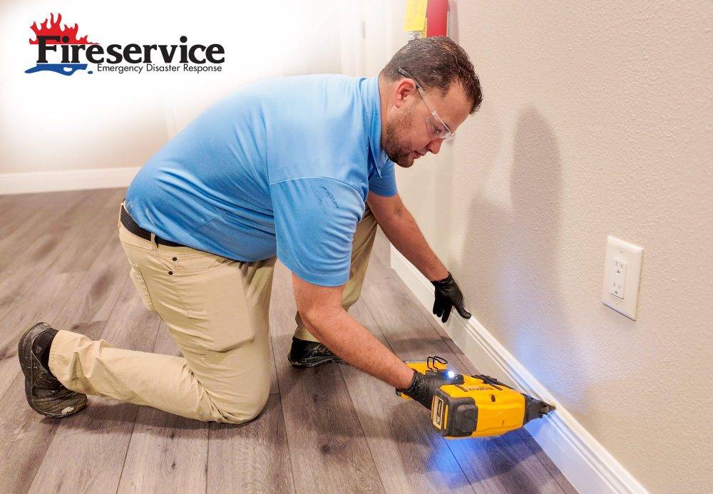 A male Fireservice contractor repairing baseboard.