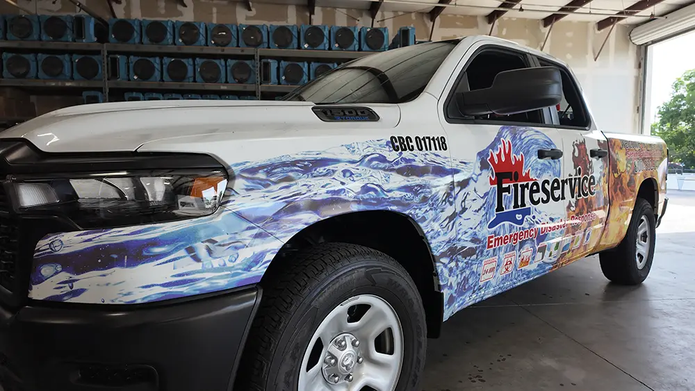 White fire service SUV with blue and orange flame graphics, parked indoors.