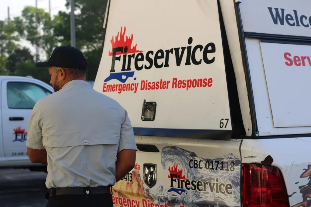 A uniformed emergency responder stands beside a white Fire Service emergency disaster response van.
