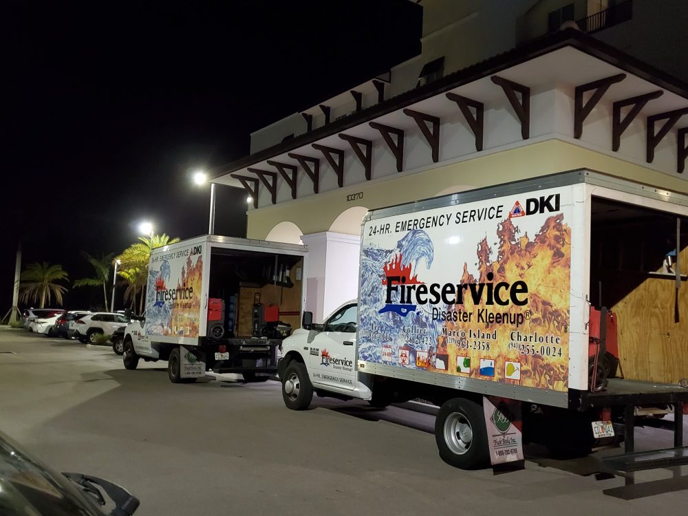 Two Fireservice trucks in front of a business at night.