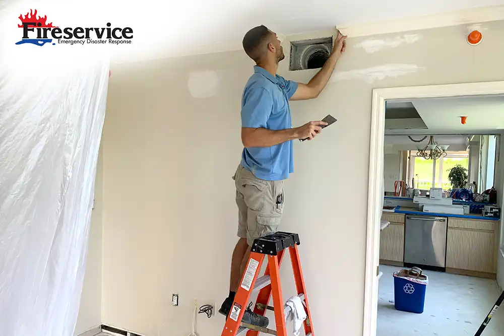 Contractor fixing crown molding while standing on a ladder.